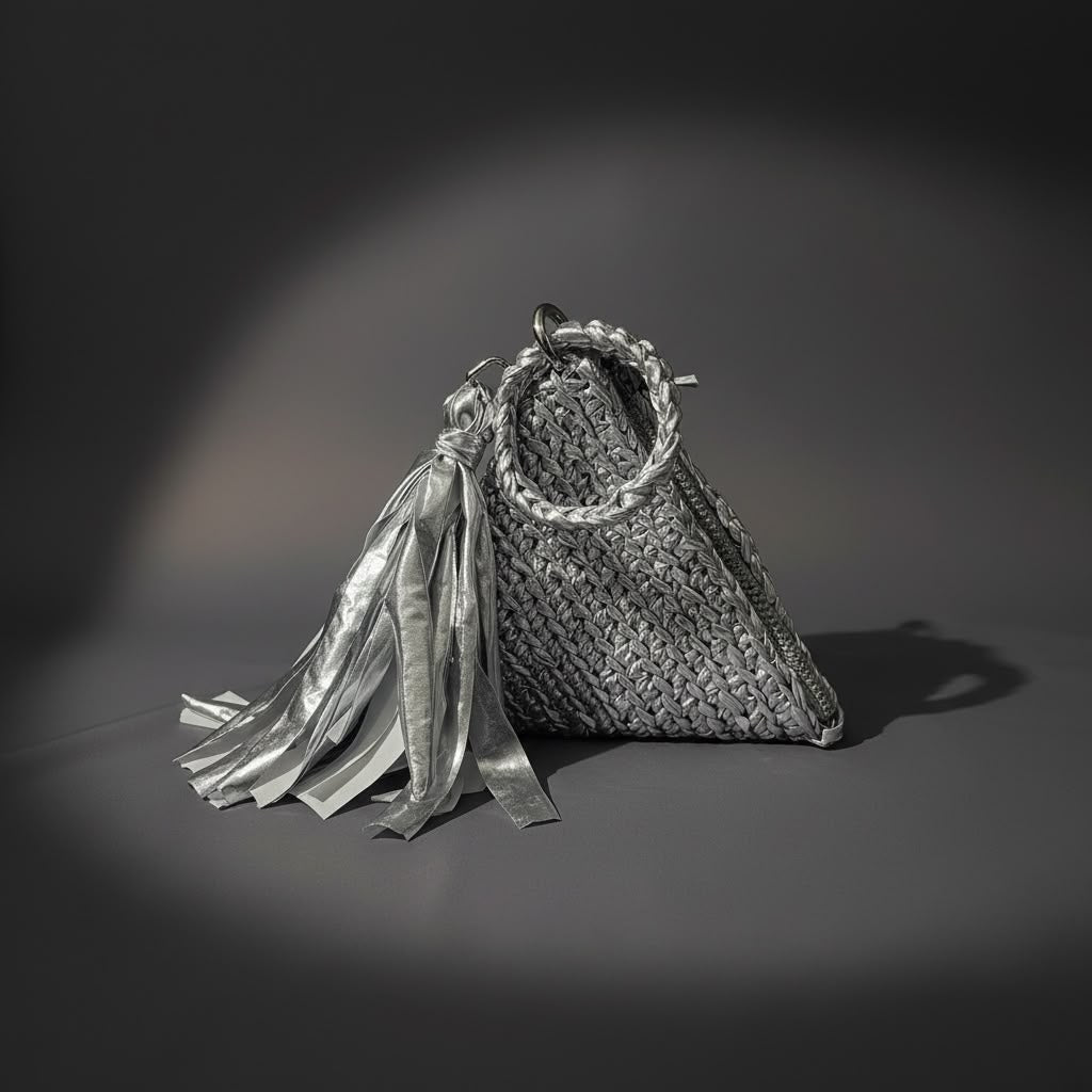 Silver upcycled t-shirt yarn crochet pyramid clutch with tassel on grey backdrop
